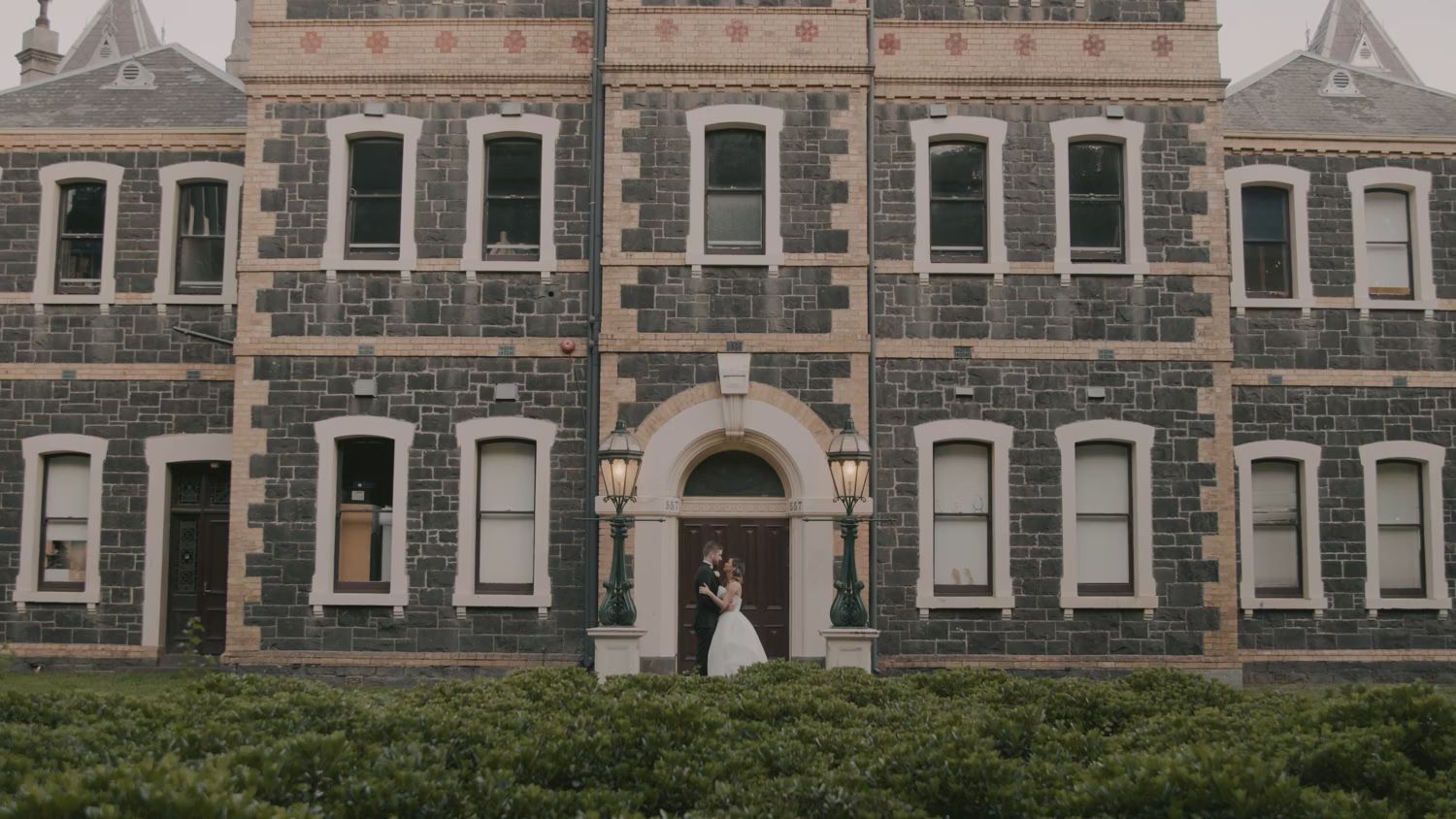 Bride and groom standing in front of a historic stone building